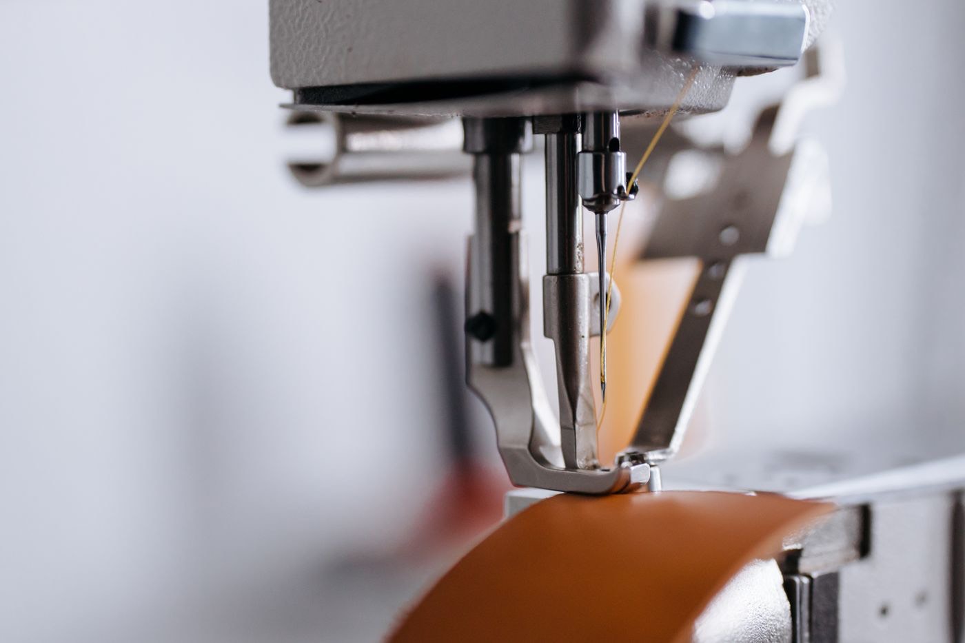 Industrial needle stitching a length of cognac harness leather